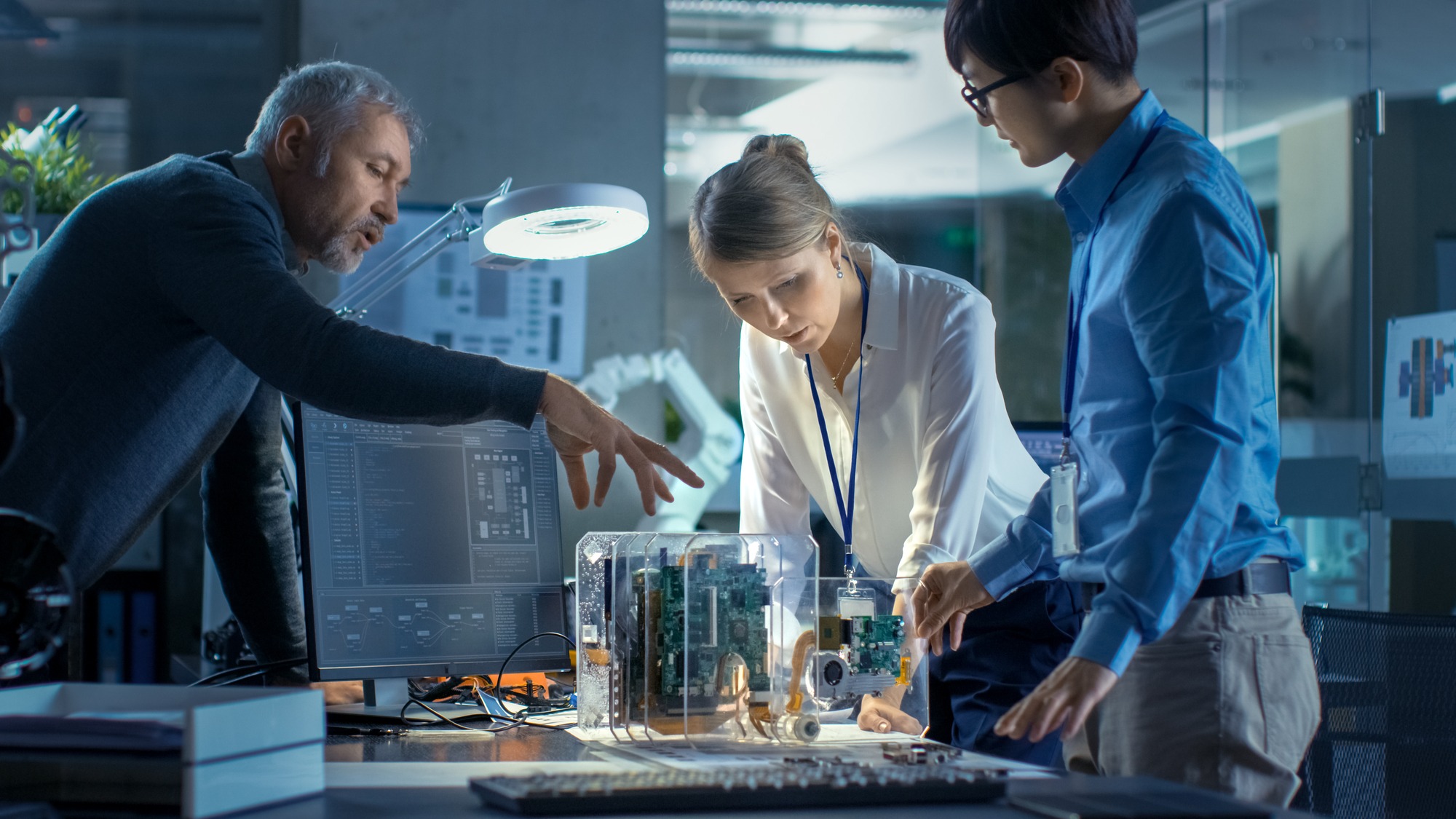 Team of Computer Engineers Lean on the Desk and Choose Printed Circuit Boards to Work with