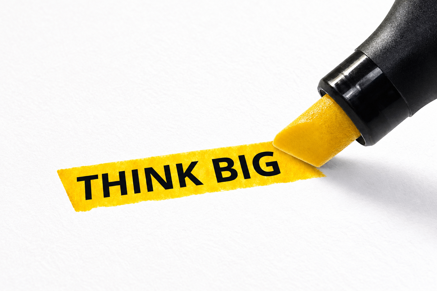 A yellow highlighter marking the phrase "THINK BIG" on white paper, emphasizing a motivational message for goal-setting and inspiration.